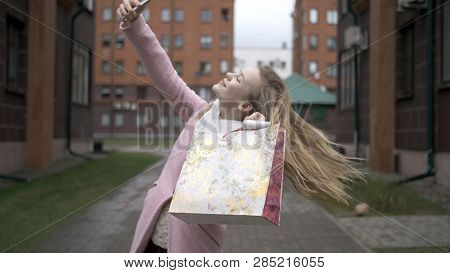 Young Happy Blonde Girl After Shopping Doing Selfie With Bright Packages