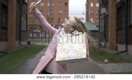 Young Happy Blonde Girl After Shopping Doing Selfie With Bright Packages