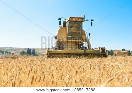Harvester In The Foreground On Rustic Background Working In The Field