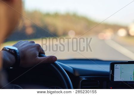European Man Is Searching Appropriate Route While Driving A Car, He Is Using His Smartphone. Insight
