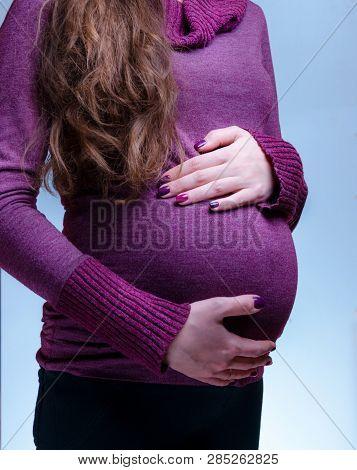 Full Length Of Caucasian, Pregnant Woman Stay In Studio. Close Up On The Stomach. Hand With Manicure