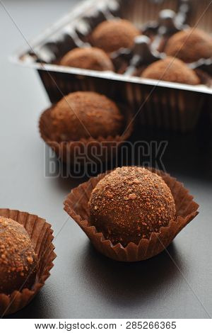 Chocolate Petit Fours Over Black Background. Top View.