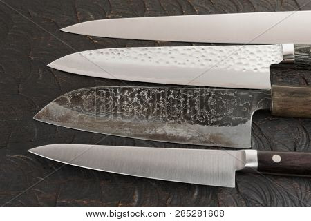 Four new and used knives on black cutting board