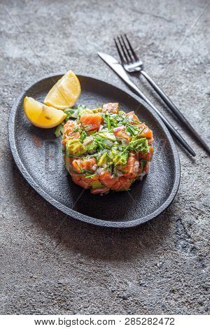 Peruvian Nikkei Food. Salmon Avocado Ceviche On Black Plate, Black Background Top View