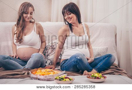 Two Pregnant Women Eating Pizza And Salad At Home