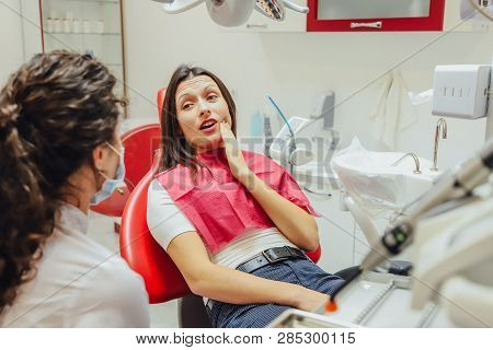 Close-up Portrait Of A Sad Young Girl With A Painful Tooth, A Doctor In Office Chairs, An Isolated D