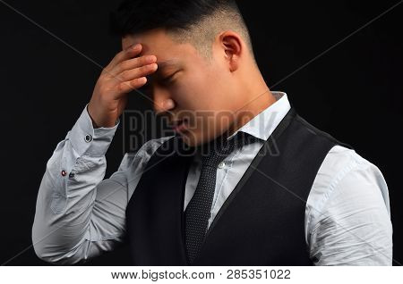 A Thoughtful Asian Man, Put His Hand To His Head, As If He Had A Headache