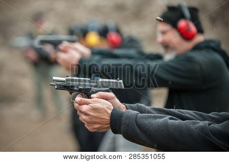Close-up Detail View Of Shooter Hold Handgun In Row Group Of People On The Shooting Range