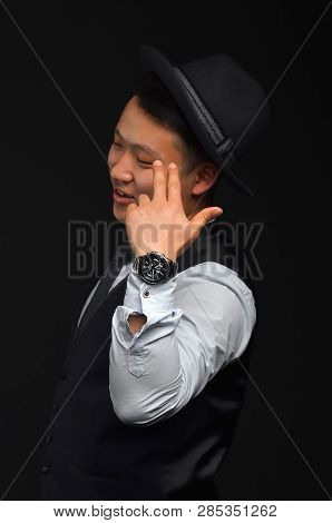 A Young Asian Man In A Black Hat, Closed His Eyes And Put His Fingers Against His Head Like A Pistol