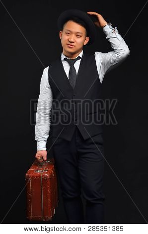 A Photo Of An Asian Man In Full Height, He Carries A Brown Suitcase And Raises His Hat By Congratula