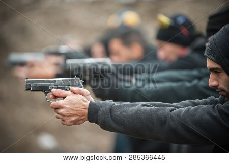 Close-up Detail View Of Shooter Hold Handgun In Row Group Of People On The Shooting Range