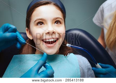Cheerful Positive Child Sit In Dental Chair. Hands In Latex Gloves To Floss Front Teeth. Woman Asiss