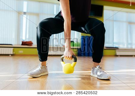 Athletic Woman Exercising With Kettle Bell While Being In Squat Position. Muscular Woman Doing Cross