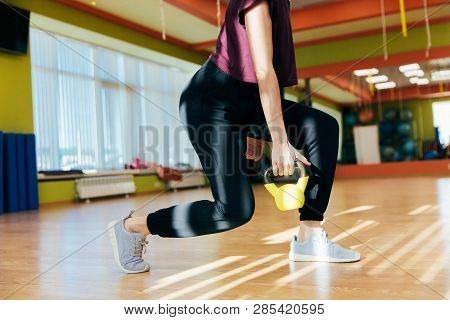 Athletic Woman Exercising With Kettle Bell While Being In Squat Position. Muscular Woman Doing Cross