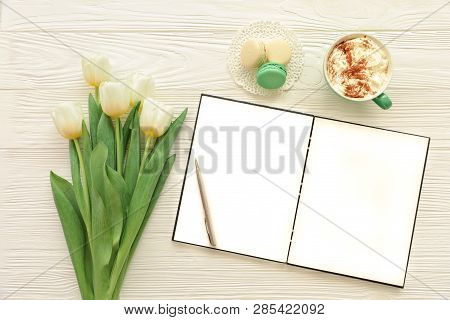 Beautiful Bouquet Of White Tulips, Empty Open Notebook, Silver Pen, Cup Of Cappuccino, Makaroons On 