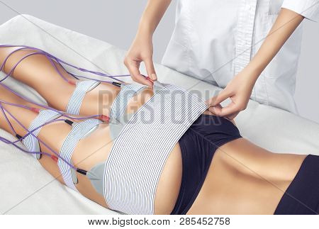 The Procedure Of Myostimulation On The Legs And Buttocks Of A Woman In A Beauty Salon. Caring For Th