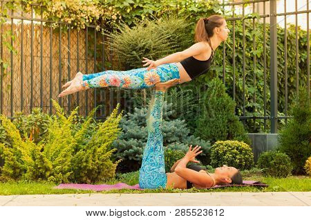 Two Young Women Practicing Acro Yoga Outdoors
