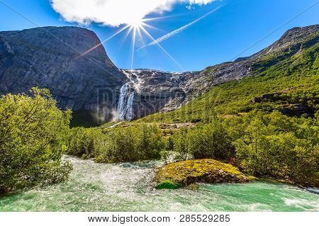 Waterfall, River And Green Trees On The Way To Briksdal Or Briksdalsbreen Glacier In Olden, Norway