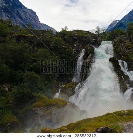Panoramic View To Kleivafossen Waterfall On Briksdalselva River, Briksdalsbreen Glacier, Norway
