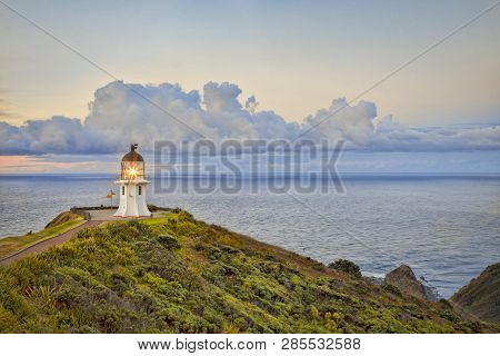 Cape Reinga Lighthouse, Northland, New Zealand, With Its Light On At Twilight.