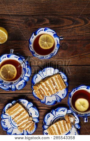 Holiday Still Life. Plates With Pieces Of Tasty Cake And Cups Of Tea With Lemon On Grunge Wooden Bac