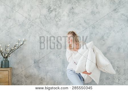 Feather Pillow Comfort. Young Satisfied Blonde Woman Holding Pile Of Pillows. Copy Space On Grey Bac