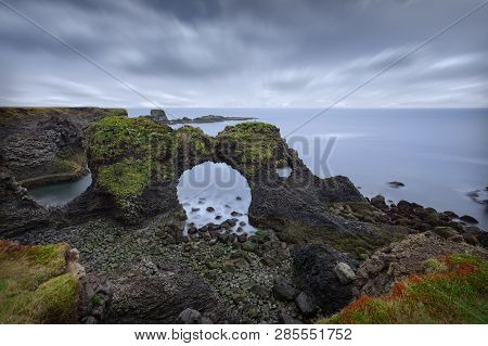 Iceland Landscape Scene Of Famous Arnastapi Arch Rock And Cliffs At Cloudy Morning As Long Exposure 