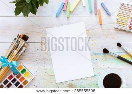 Creative Workplace For Painting Concept, Paint Brushes, Paintbox With Watercolors, Crayons, Coffee A