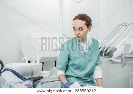 Selective Socus Of Thoughtful Female Dentist Sitting In Dental Clinic