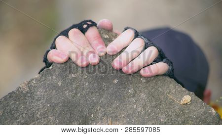Young Alpinist Climbing On A Stone. Man Wearing Cap, Yellow T-shirt And Gloves Overcomes Difficult N