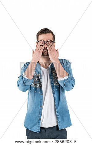 Isolated Portrait Of Bearded Young Man In Casual Clothes And Glasses Covering His Eyes With Hands. C