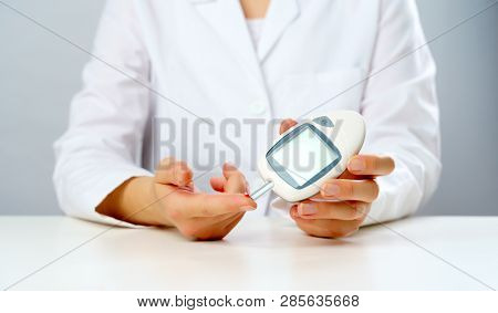 Picture of doctor's hand with glucometer.