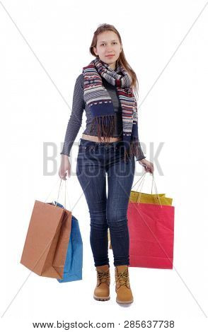 Front view of a woman walking with shopping bags. beautiful girl in motion.  Frontside view of person.  Shopping  people collection. Isolated over white. A smiling girl in a scarf carries shopping.
