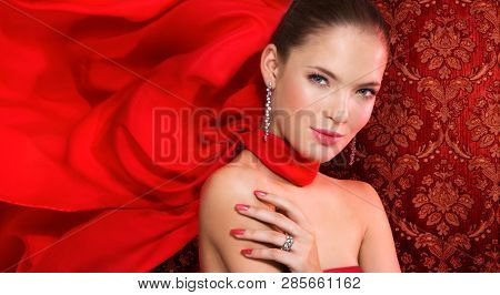 Lady in silk scarf with diamod jewellry on damask wallpaper background 