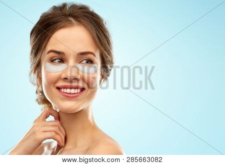 beauty, cosmetology and rejuvenation concept - beautiful young woman face with hydrogel under-eye patches over blue background