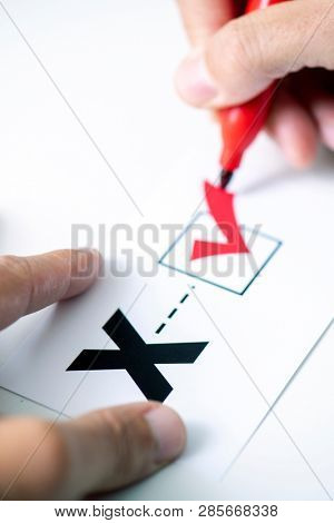 closeup of a young caucasian person doing a check mark on a paper with a X written in it, for the third gender category 