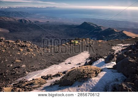 a green tent on the edge of Schiena dell'Asino ridge; high altitude landscape on Bove Valley and sicilian coast