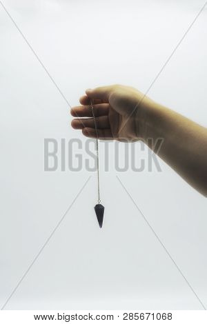 Pendulum Dowsing On An Isolated White Background With An Amethyst Crystal.