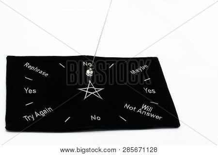 Pendulum Dowsing On An Isolated White Background With A Silver Point And A Black Dowsing Matt.