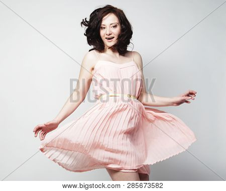 young brunetee  woman wearing pink dress and posing over white background