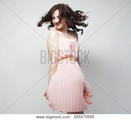 young brunetee  woman wearing pink dress and posing over white background