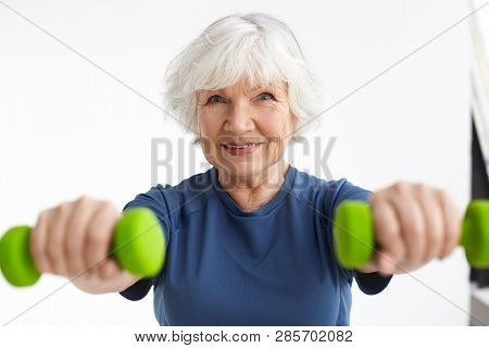 Active Energetic Happy Elderly Caucasian Female With Gray Hair Enjoying Physical Exercises Indoors, 