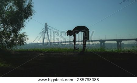 A Guy Is Doing Part Of His Workout. He Is Stretching His Spine Bending Down And Forward. He Is Train
