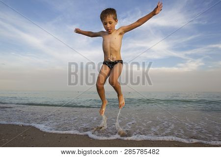 The Child Jumps Out Of The Water. The Boy Jumps On The Ocean. Vacation At The Seaside