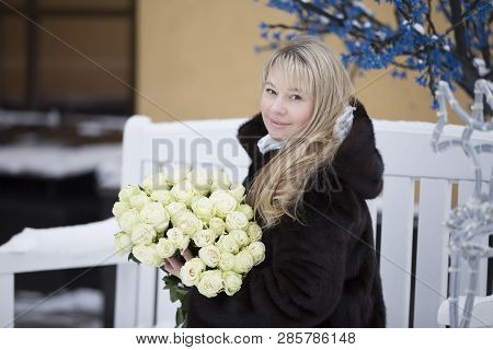 An Ordinary Woman In A Mink Coat With A Bouquet Of Flowers
