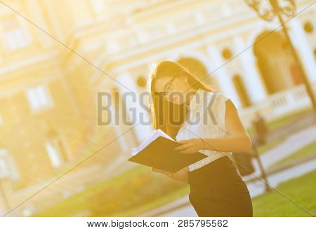 Ashionable Business Woman Holding A Blank Of Paper In Her Hands And Posing On The Camera. The Workin