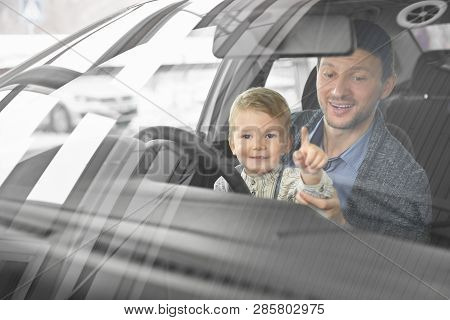 Front View Through Windshield Of Father And Son Sitting In Drivers Seat Of Automobile And Observing 