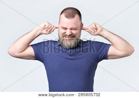 Senior Man, Covering Closed Ears Annoyed By Loud Noise Not Wanting To Hear Story