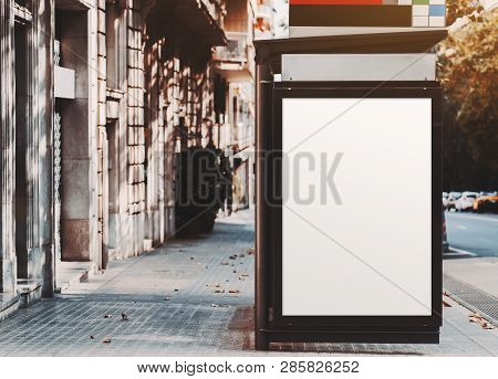 A Poster Placeholder Inside Of City Bus Stop Near The Road; Vertical Blank Advertising Banner Mock-u
