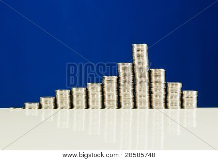 เหรียญซ้อนกันอยู่ในบาร์กับพื้นหลังสีน้ำเงิน